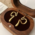 Polished gold curved snake-style ear cuffs displayed in a premium wooden jewelry box - Gold