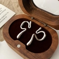 Detailed view of silver wave-shaped ear cuffs on a brown velvet jewelry tray - Silver