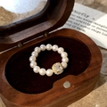 Macro shot of an elegant pearl beaded ring with a sparkling crystal center in a wooden box - White