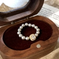 Macro shot of grey pearls and square-cut zircon stone on golden ring in a wooden box - Gray