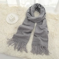 Soft light grey winter scarf with long fringes shown on a cozy white plush surface - Light Heather Grey