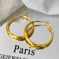 Detalle de pendientes de aro dorados de cuerda trenzada con reflejo metálico en espejo - Dorado
