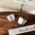Close-up of matte silver geometric earrings with brushed metal texture on a wooden tray - Brushed Stud Earrings / Silver