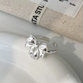 Macro shot of silver bow open ring with beaded edges on a white ceramic plate - Silver Bow Ring