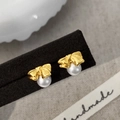 Detalle de pendientes de lazo dorado con perlas blancas y acabado de metal cepillado - Dorado