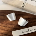 Macro shot of silver brushed metal geometric stud earrings on a walnut wood tray - Silver Brushed Stud Earrings