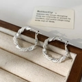 Detail van zilveren gedraaide oorringen met glitterstructuur in een houten sieradendoosje - 2,5 cm Creolen / Zilver