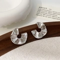 Detail van waaiervormige zilveren oorbellen met geplooide textuur en zirkonia-accenten - Zilver