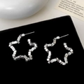 Détail de boucles d'oreilles étoile argentées au design géométrique sur velours noir - Argenté