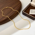 Vue macro détaillée d'un collier chaîne doré à texture givrée sur un plateau en noyer - Chaîne Fine avec Fermoir à Ressort / Collier Or