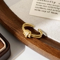 Close-up of golden double-layer knot ring with micro-set zircons on a rustic backdrop - Gold Double Layer Twisted Zirconia Ring