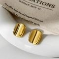 Macro shot of minimalist gold geometric rectangular stud earrings with mirror finish - Gold