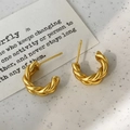 Dettaglio macro di orecchini a cerchio ritorti dorati opachi con design a C ed elegante - Stile a Spirale Opaco / Oro