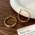 Detailansicht der goldenen Doppel-Creolen mit elegantem Klappverschluss auf Holztisch - 3cm Creolen / Gold