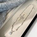 Dettaglio di un'elegante collana di perle con pendente in zircone su velluto beige - Collana di perle e zirconi bianchi
