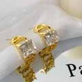 Macro shot of gold chain earrings with large square zircon stones on reflective surface - Gold White Zircon Stud Earrings