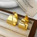 Macro shot of polished gold chunky C-shaped hoop earrings on a velvet display tray - Gold