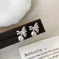 Dettaglio degli orecchini a fiocco in argento con zirconi e perle a goccia eleganti - Argento