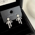 Vue détaillée des boucles d'oreilles rose argentée avec nœud en dentelle dans un écrin - Style Nœud Fleur Argent