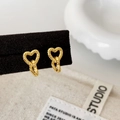 Detalle de pendientes de corazón dorados con anillos entrelazados en un soporte de terciopelo - Dorado