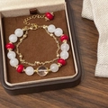 Detalle de una pulsera de doble capa con cuentas blancas, rojas y cadena dorada - Pulsera de piedra natural blanca