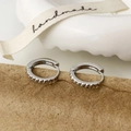 Detailed close-up of silver huggie earrings with unique serrated engraving on kraft paper - Silver Minimalist Ear Buckle