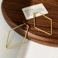 Detailed view of geometric rhombus earrings with golden brushed texture on a wooden tray - Gold Large Rhombus Earrings