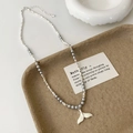 Close-up of pearl and silver bead necklace with a white fishtail pendant on a tray - Grey High Bright Pearl White Whale Tail Necklace