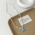 Close-up of blue enamel fishtail pendant and silver beads on a pearl necklace - White High Bright Pearl Blue Whale Tail Necklace