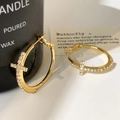 Detailaufnahme goldener Creolen mit funkelndem, zirkonbesetztem Kreuzanhänger - 3cm / Gold