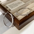 Detailaufnahme silberner Creolen mit funkelnden Zirkonia-Kreuzanhängern in einer Schmuckschatulle - 4cm / Silber