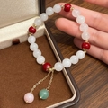 Detailed shot of beaded bracelet with red stones and elegant golden double tassels - White Natural Stone Bracelet