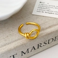 Primer plano de anillo nudo dorado mate sobre lino con diseño minimalista moderno - Dorado Mate