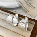 Detailed macro view of silver-toned C-shape earrings with a brushed matte metal finish - Silver Brushed Stud Earrings