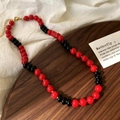 Dettaglio della collana di perle in vetro rosso e nero con chiusura a moschettone oro - Nero/Rosso