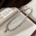 Gros plan d'un collier de perles grises avec pendentif gemme jaune sur un plateau bijoux - Collier Perle Grise Zircon Jaune