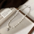 Détail d'un collier de perles élégant avec pendentif zircon sur plateau velours - Collier Perle Blanche Zircon Blanc