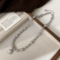 Détail du collier de perles grises avec pendentif zircon carré sur plateau en lin - Collier Perle Grise Zircon Blanc