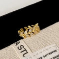 Macro shot of gold leaf ring with zircon stones on premium fabric background - Gold