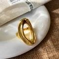 Makro-Detail eines glänzenden goldenen ovalen hohlen Rings auf weißer Keramik und Leinen - Gold