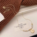 Retro gold necklace with tiger eye sun pendant and white pearls on brown knit - Cat's Eye Sun Pendant Style