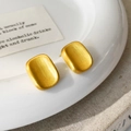 Macro view of matte gold square earrings with fine brushed texture on ceramic tray - Brushed Stud Earrings / Gold