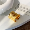 Macro view of wide gold open ring featuring unique lava texture on ceramic display - Gold