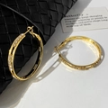 Macro detail of gold hoop earrings with white zircon pavé setting on woven texture - Gold