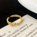 Macro detail of gold-plated open ring with white pearl and zircon accents on card - Adjustable Open / Gold Cross Zirconia