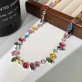 Detalle macro del collar con circonitas multicolores y gemas brillantes en bandeja madera - Collar de circonia multicolor plateada