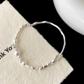 Détail du bracelet en perles argentées montrant des perles métalliques et blanches - Style Perle Blanche