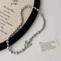 Détail d'un collier de perles grises avec pendentif papillon pavé étincelant - Collier en Perles Papillon Gris (B-156)