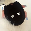 Dettaglio di orecchini a farfalla con micro-pavé in una scatola di velluto elegante - Orecchini a lobo farfalla argentati