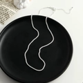 Détail macro d'une chaîne argentée scintillante avec fermoir mousqueton sur fond noir - Collier en Argent